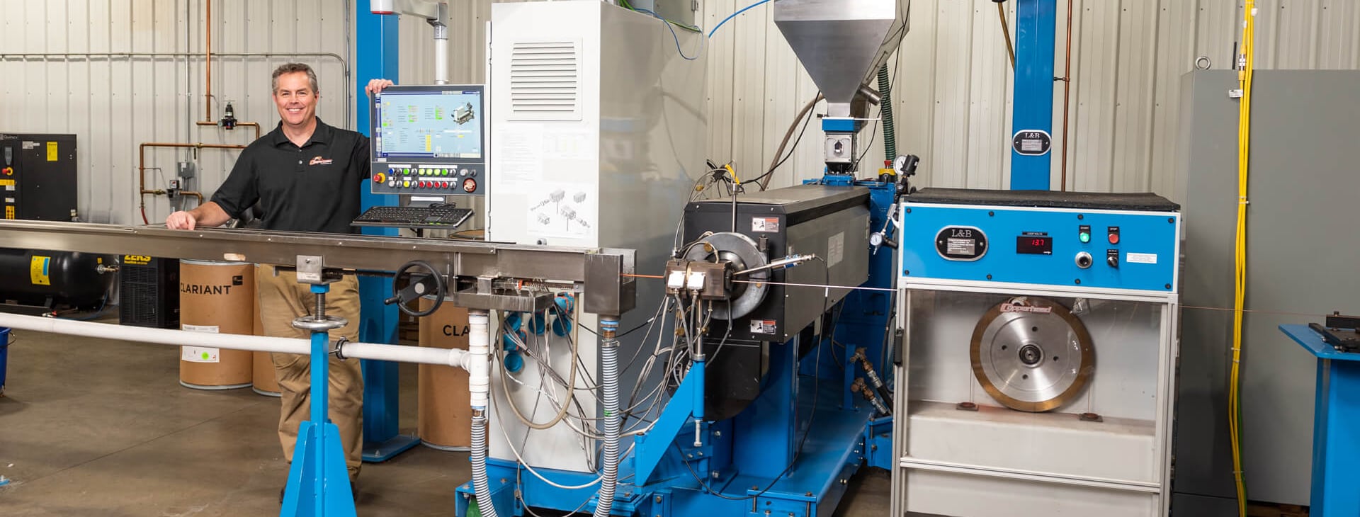 A male in blue collared polo shirt is sitting behind counter with robotic machinery