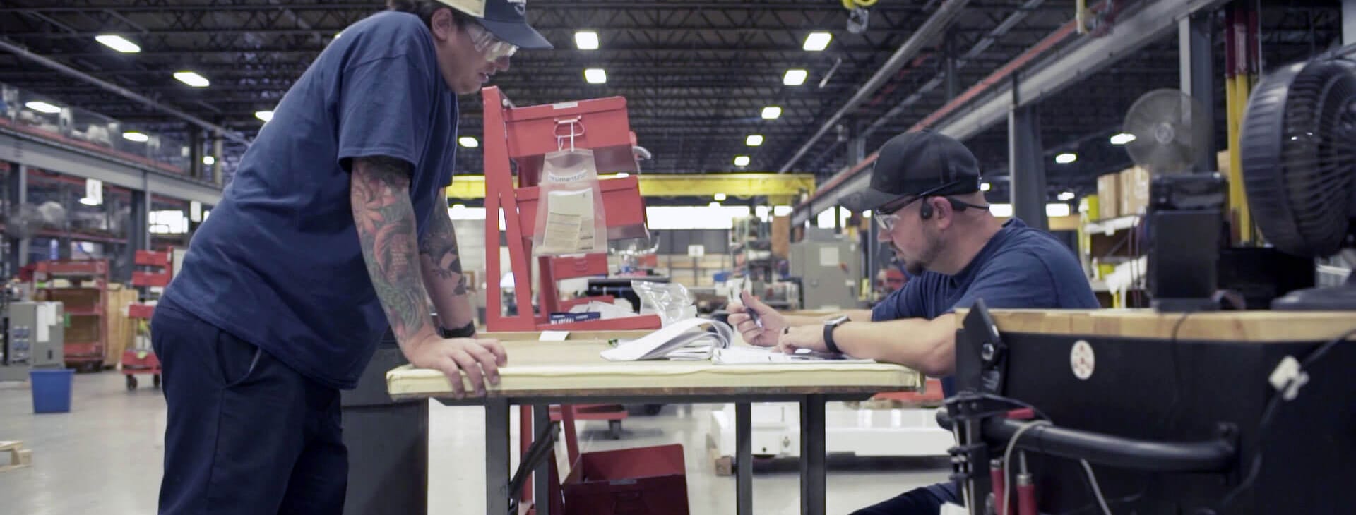Two graham engineering people working at a table on the factory floor
