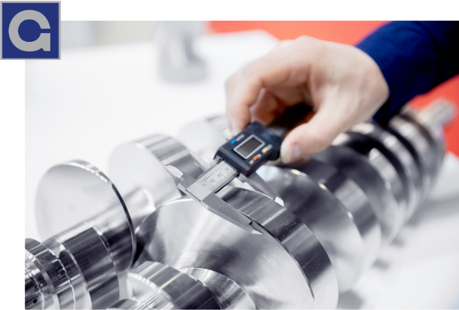 A tightly focused shot showing a maintenance engineer's hand using an electronic caliper to measure the exact width of a machine part.